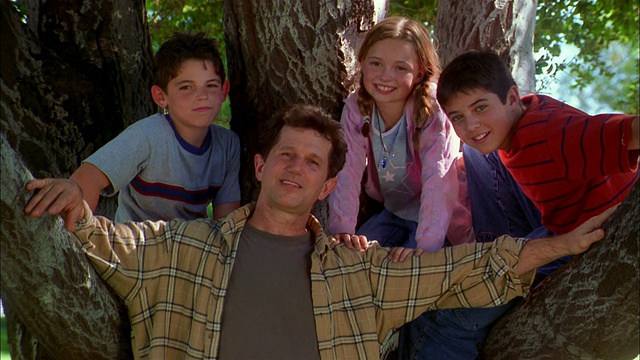 中镜头的父亲和两个儿子和女儿在树旁的CAM微笑视频素材