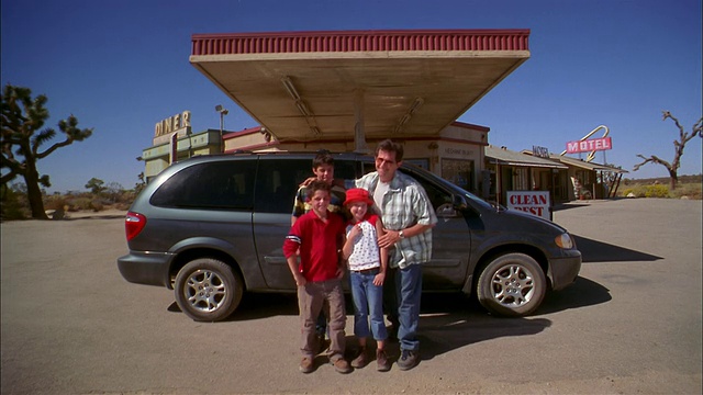中镜头的父亲和孩子们在停在加油站的小货车前摆姿势视频素材