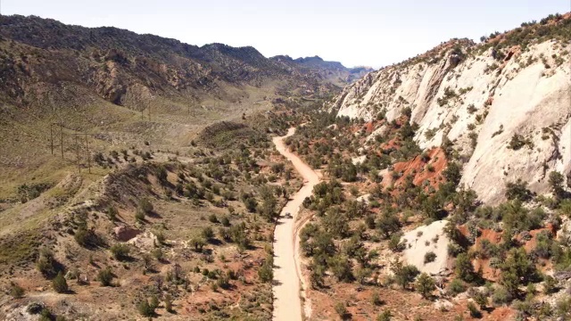 宽高角天桥跟踪拍摄的汽车行驶在蜿蜒的沙漠道路/大楼梯埃斯卡兰特国家纪念碑，犹他州，美国视频素材