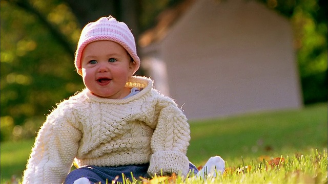 中镜头婴儿在毛衣和针织帽坐+微笑户外视频素材