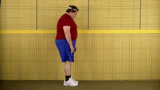 中等大小的胖子在锻炼，试图摸脚趾视频素材