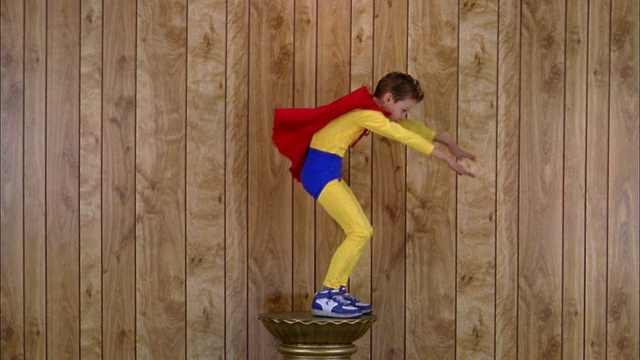 中镜头男孩在超级英雄服装站在基座上假装飞翔视频下载