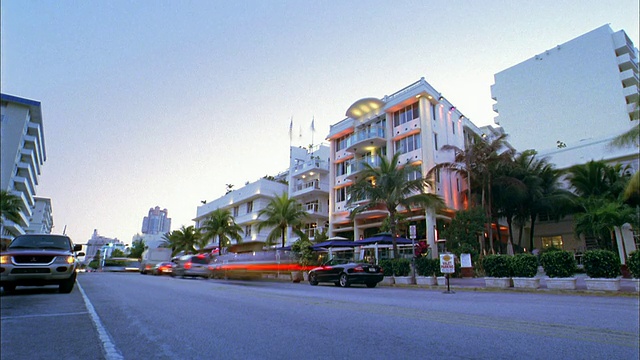宽镜头时间流逝交通通过建筑物和棕榈树从白天到晚上/迈阿密海滩，佛罗里达视频素材