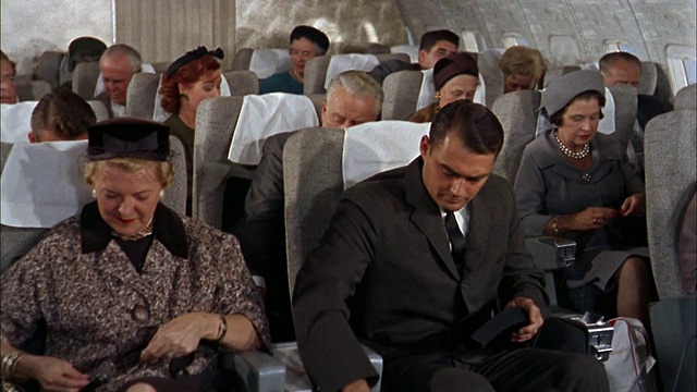 20世纪60年代，707飞机上的乘客系着安全带，男乘客一边抽烟一边聊天视频素材