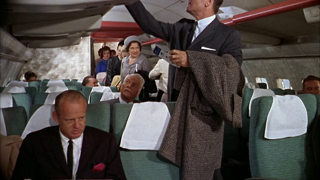 20世纪60年代，中镜头乘客在707飞机上找到座位，把行李放在行李架上视频素材