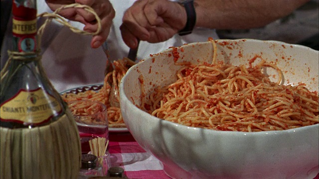 20世纪60年代近距离混合和提供意大利面+番茄酱从碗/平底锅到男人微笑+吃视频下载