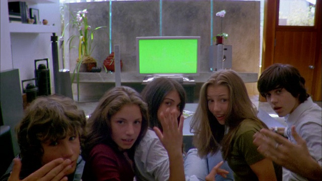 画面中，十几岁的男孩和女孩在客厅看绿色屏幕的平板宽屏电视视频下载