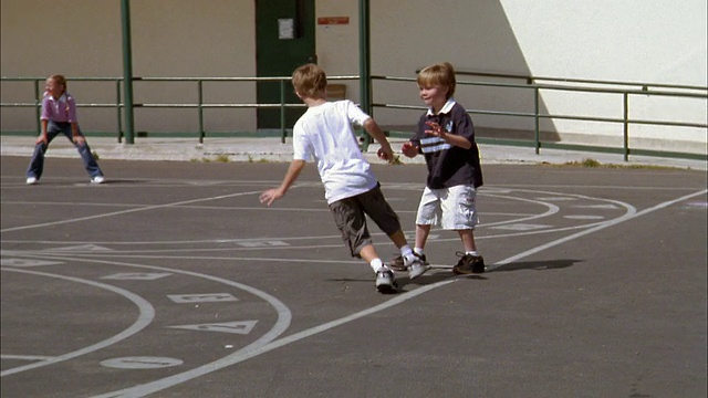 中等射击跟踪射击男孩踢球和跑垒在操场上的踢球比赛视频素材