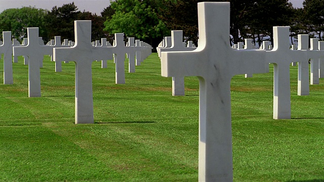 低角度摄影车拍摄的大理石十字架在绿色草地上的美国公墓/诺曼底视频下载
