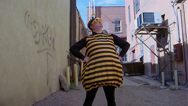 中镜头倾斜下来的人穿着蜜蜂服装站在小巷视频素材