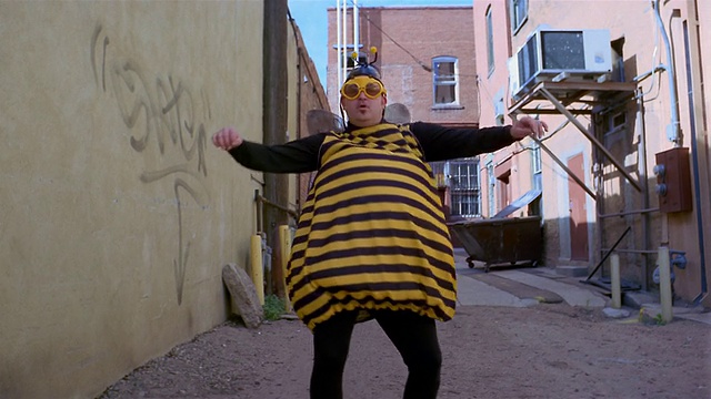 中景男子穿着蜜蜂服装在巷子里跳舞视频素材