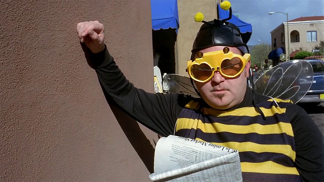 中景放大在男人穿着蜜蜂服装读报纸视频素材