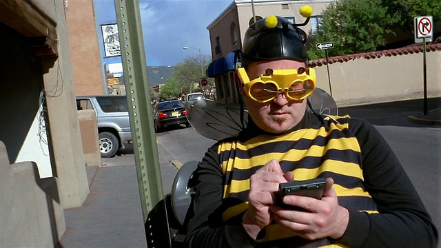 中镜头男子穿着蜜蜂服装使用个人手持装置视频素材