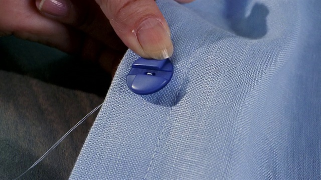 近缝蓝色纽扣在蓝色织物上视频下载