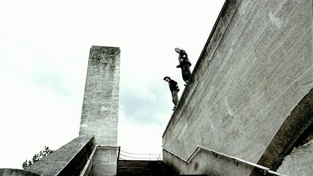 低角度广角两名自由跑动者从屋顶跳下，抓住窗台/拉起自己视频素材
