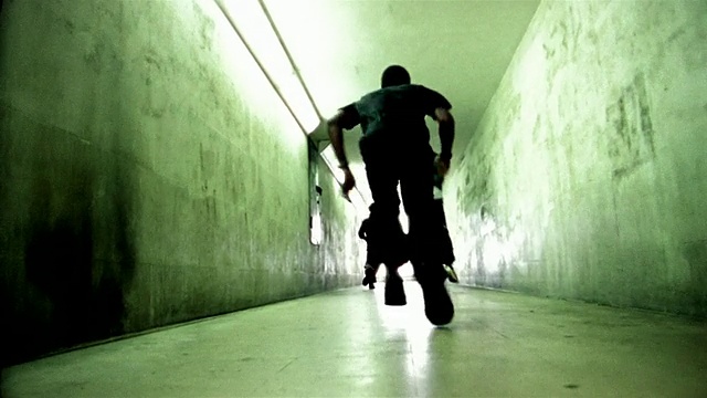 低角度远射三名自由跑动者沿着走廊跑离摄像机/跳墙视频下载