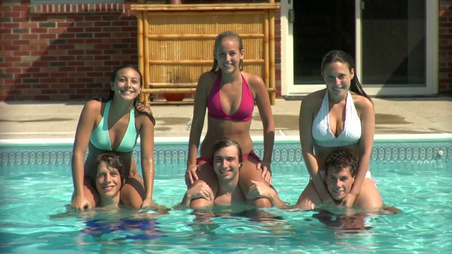 在美国新泽西州米德尔塞克斯的肖像游泳池里，三个年轻女人坐在男人的肩膀上视频下载