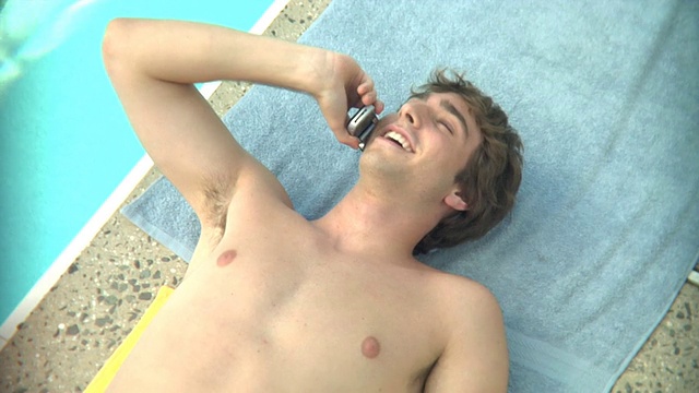 美国新泽西州米德尔塞克斯市，16-17岁的少年躺在泳池边打电话视频素材