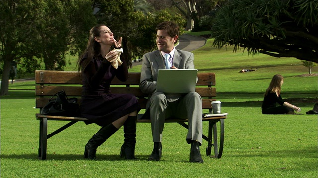 澳大利亚悉尼，两名商务人士坐在公园长椅上，一名男子正在使用笔记本电脑视频素材