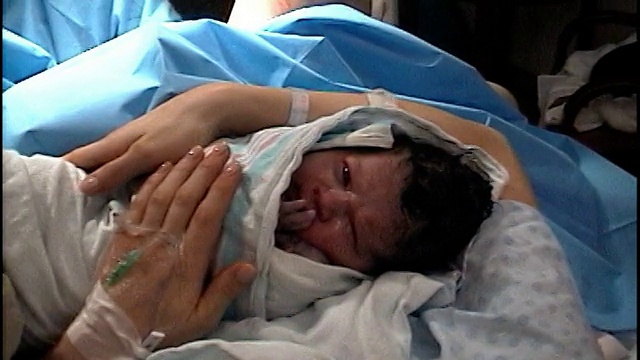 高角度靠近母亲抱着新生儿在医院的床/盘护士检查婴儿视频素材