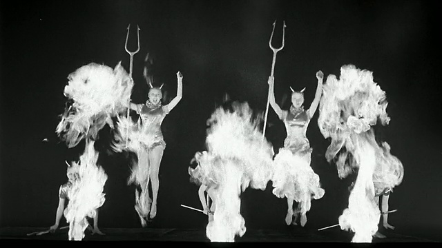 1945年B/W宽镜头五个魔鬼女人拿着干草叉跳上跳下，前景中有火焰视频下载