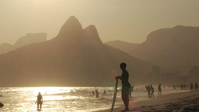日落时分，巴西里约热内卢伊帕内玛海滩上放松的人们的剪影视频素材