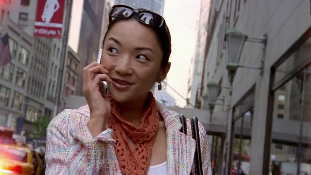 近距离的倾斜倾斜的女人讲手机和走在城市街道/纽约市视频素材