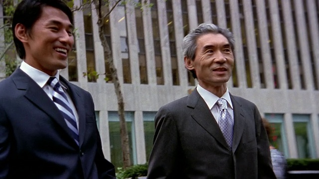 低角度中拍摄了两个商人谈话和走下台阶，背景是纽约的办公大楼视频素材