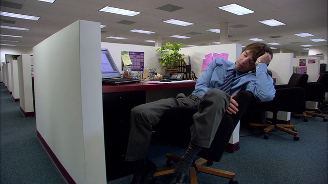 (中拍)加州洛杉矶，一名男性办公室职员睡在小隔间的椅子上视频下载