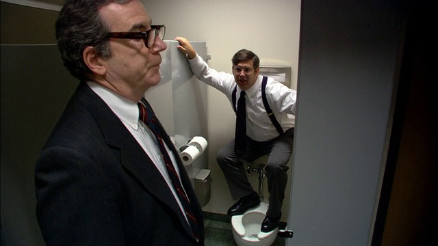 中镜头老板打开浴室隔间门/男员工躲在隔间/老板走开/低角度视频素材