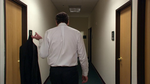 中镜头男办公室职员走在走廊上，把卫生纸粘在鞋子上/关灯/低角度视频素材