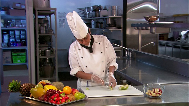 新西兰奥克兰，中杯厨师在切菜板上切水果，旁边是一盘水果视频素材