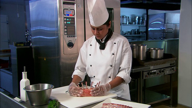 中等大小的女厨师正在厨房的砧板上切羊排，新西兰奥克兰视频素材