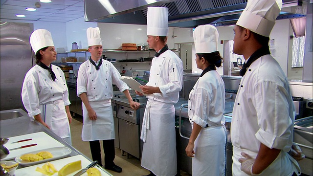 中等水平的厨师(或烹饪学生)在厨房工作/聚集在主厨身边交谈/奥克兰视频素材
