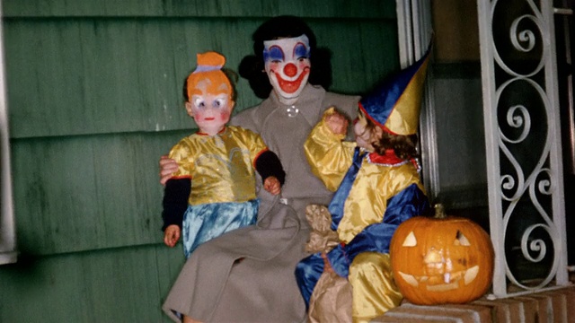 1955年，一个带小丑面具的中镜头女人和两个穿着万圣节服装的孩子向CAM招手视频下载
