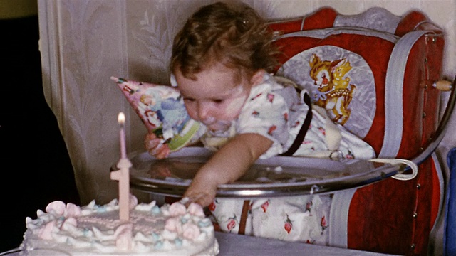1952年，一个脸上带着蛋糕的一岁小女孩从高脚椅上伸手去抓蛋糕吃视频下载
