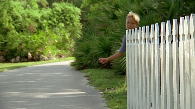 低角度中枪男孩跑棍越过白色尖桩栅栏/迈阿密，佛罗里达视频素材