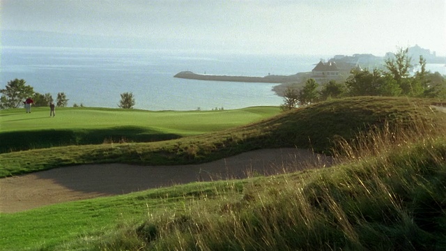 高尔夫球场上的沙坑/在绿色上行走的人/背景中的水/海湾港，密歇根州视频素材