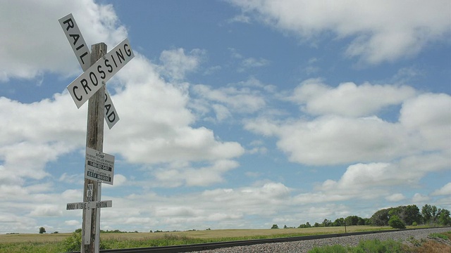北达科塔州，云掠过火车轨道和铁路十字路口标志，背景是田野视频下载