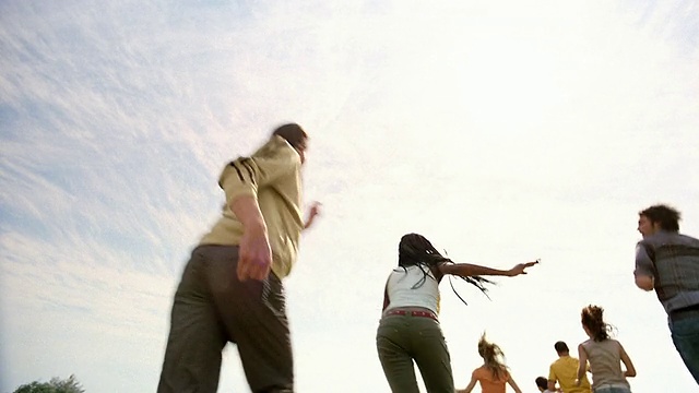 低角度广角拍摄天空/后视图的一群年轻人跑向CAM /跳过CAM /南非视频素材