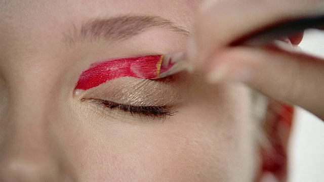 非常近距离的红色眼影涂抹在女人的眼皮上，用刷子刷/睁开眼睛+看着CAM视频素材