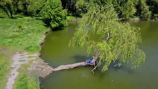 坐在柳树上，用手泼水，享受夏日的女人视频下载
