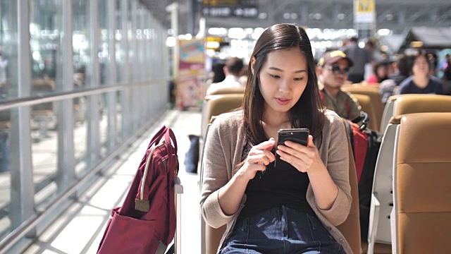 年轻女子在等飞机的时候玩智能手机，慢镜头视频下载
