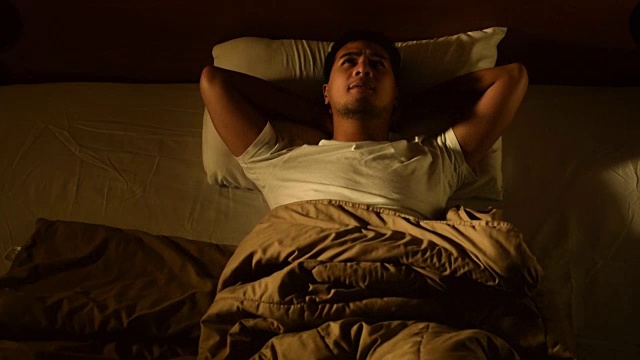 一名患有失眠的抑郁男子躺在床上的镜头，快速移动视频下载