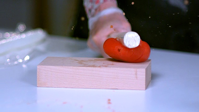 一段慢动作序列，展示了一根指挥棒被用来击碎一块木板上的西红柿。视频素材