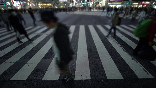一群人在夜晚穿过日本涩谷市的街道视频下载