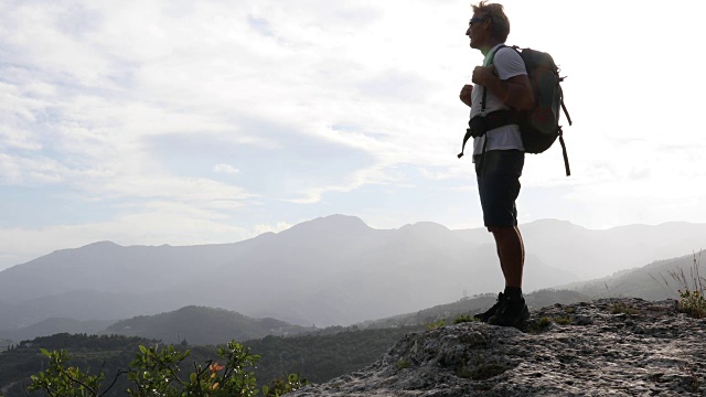 雄性徒步旅行者爬上山谷上方的岩石高处视频素材