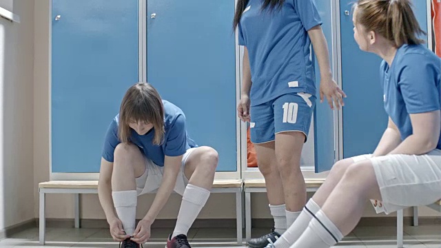 快乐的女足球运动员在更衣室里准备时聊天视频素材