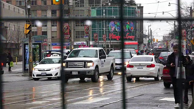 加拿大多伦多:雨天，通过建筑围栏的交通和生活方式。在市中心的贝和登达斯街的日常城市生活视频下载