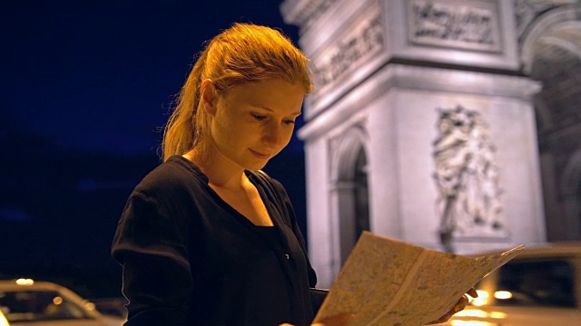 带着巴黎城市地图的游客在夜间欣赏凯旋门纪念碑视频下载